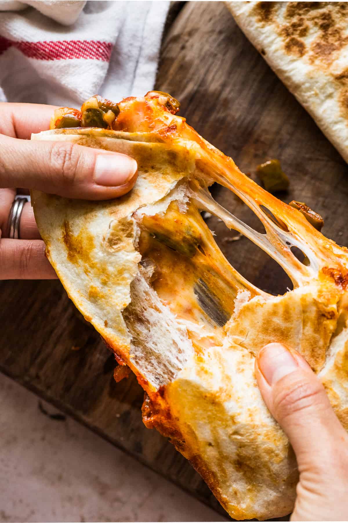 A quesadilla being pulled apart to show the stretchy cheese inside.