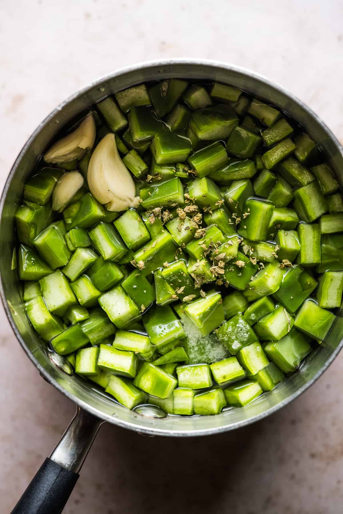 Nopales (cactus paddles) in a small pot with garlic, Mexican oregano, salt, and water.