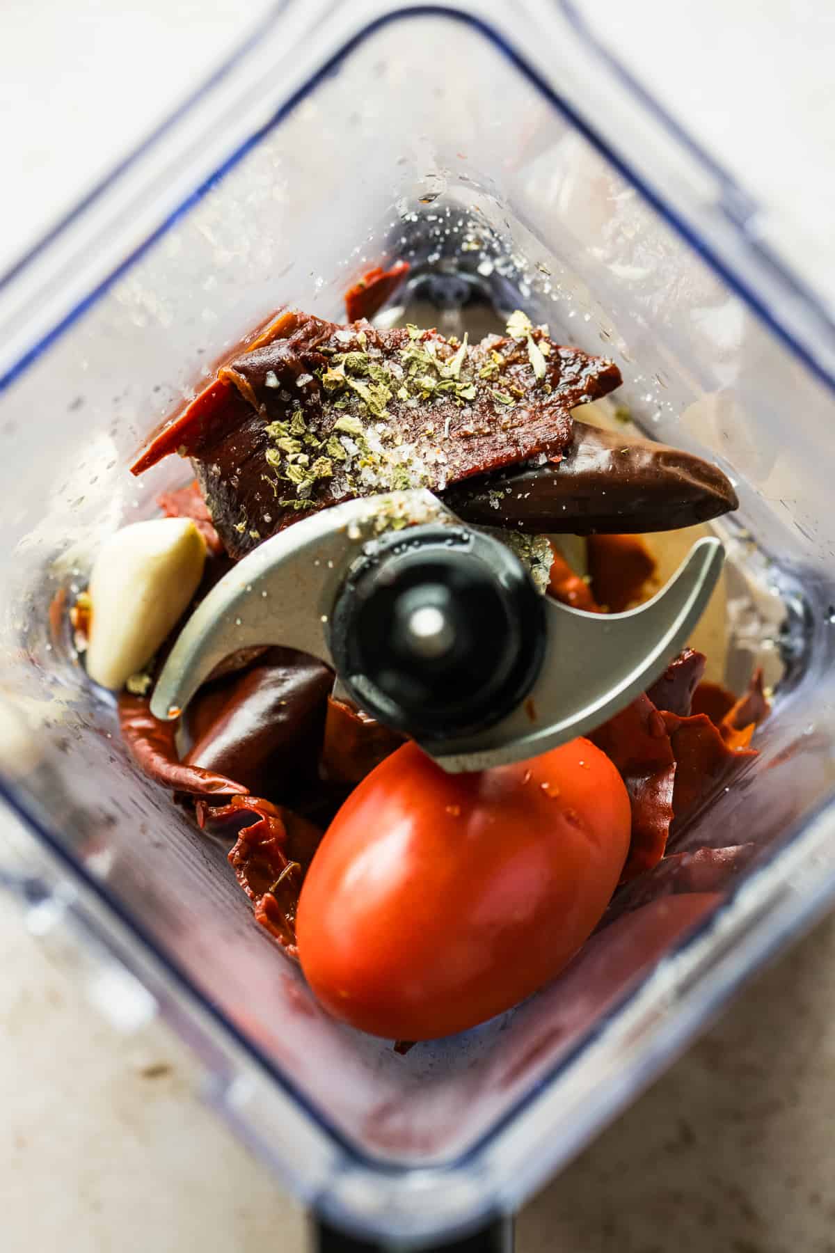 Dried chiles, onion, spices, and tomatoes in a blender.