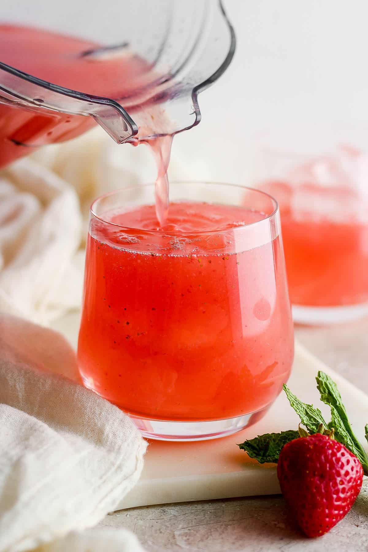 Strained agua de fresa (Strawberry agua fresca) being poured into a glass.