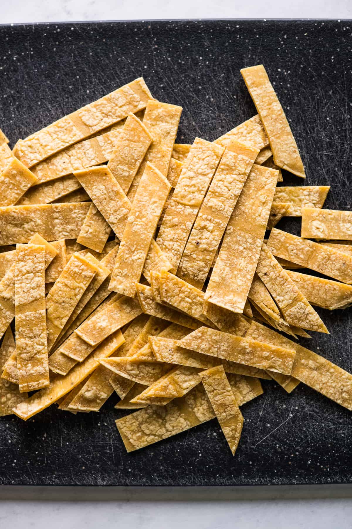 Corn tortilla strips on a cutting board.