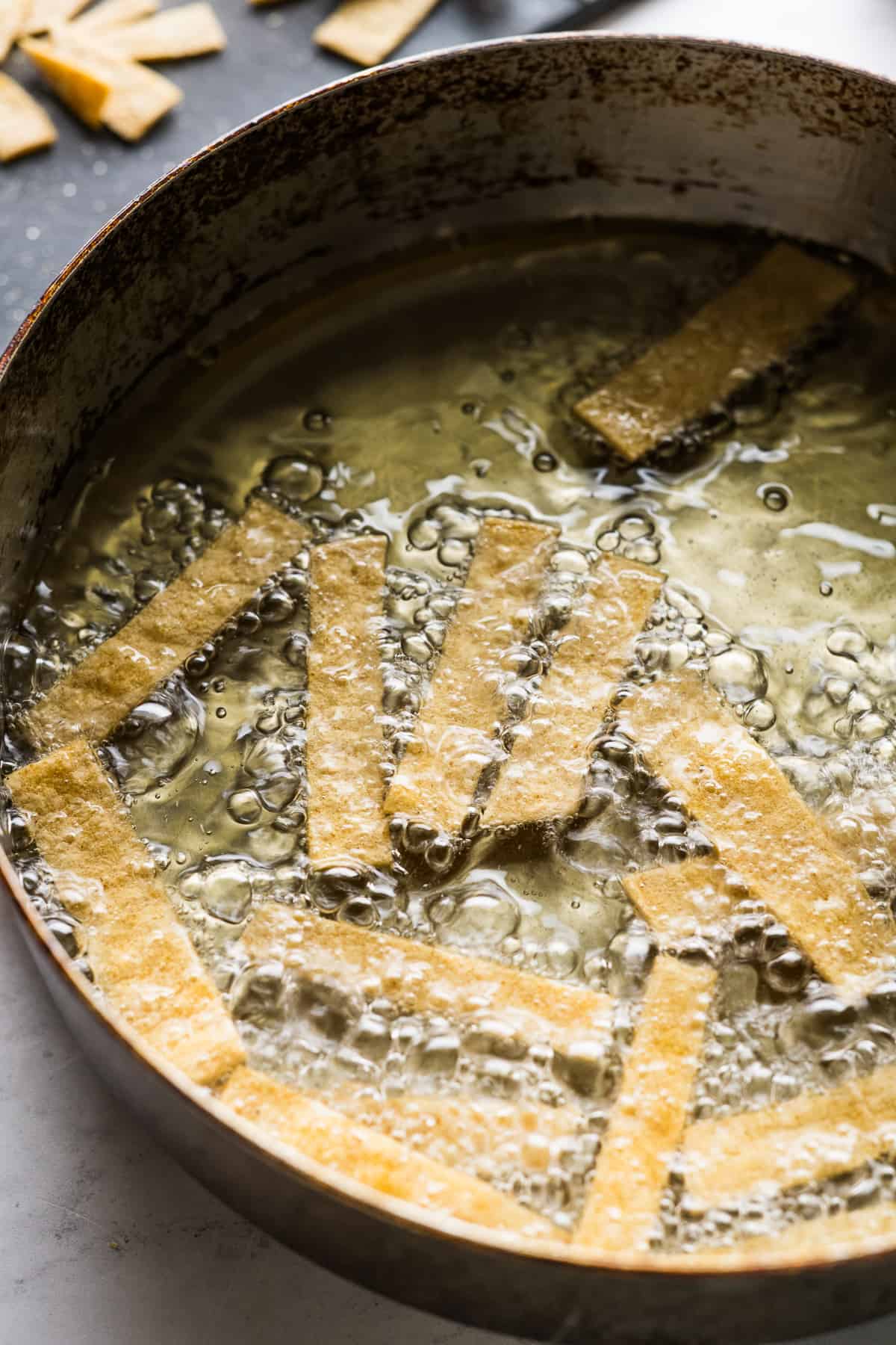 Tortilla strips being fried in a pan.