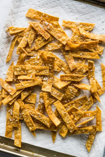 Crispy tortilla strips on a baking sheet lined with paper towels.