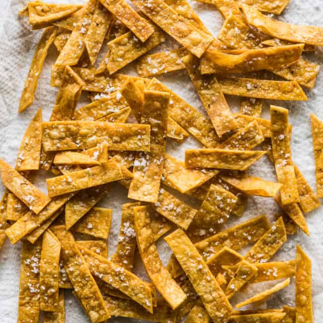 Crispy tortilla strips on a baking sheet lined with paper towels.