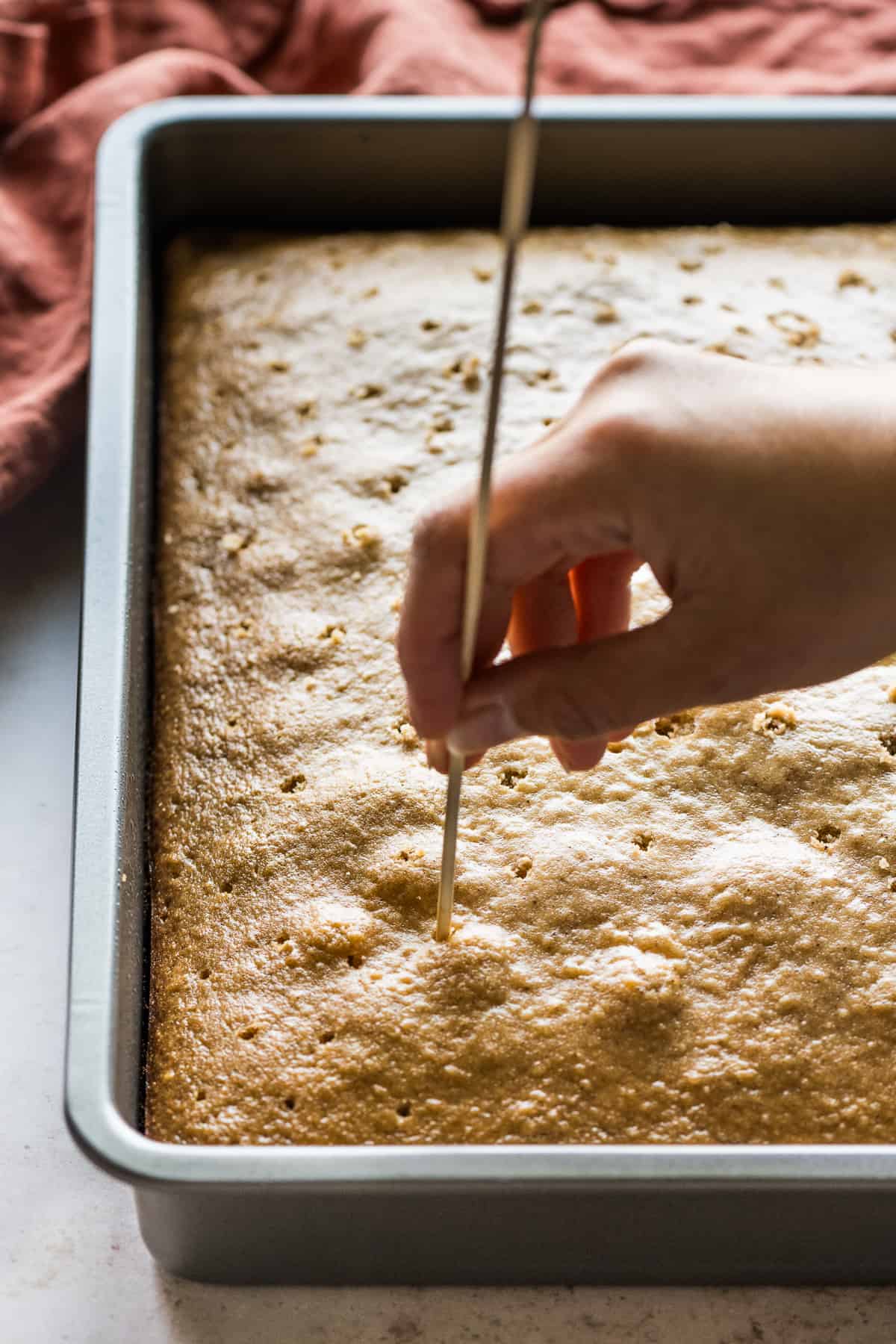 A skewer poking an apple tres leches cake.