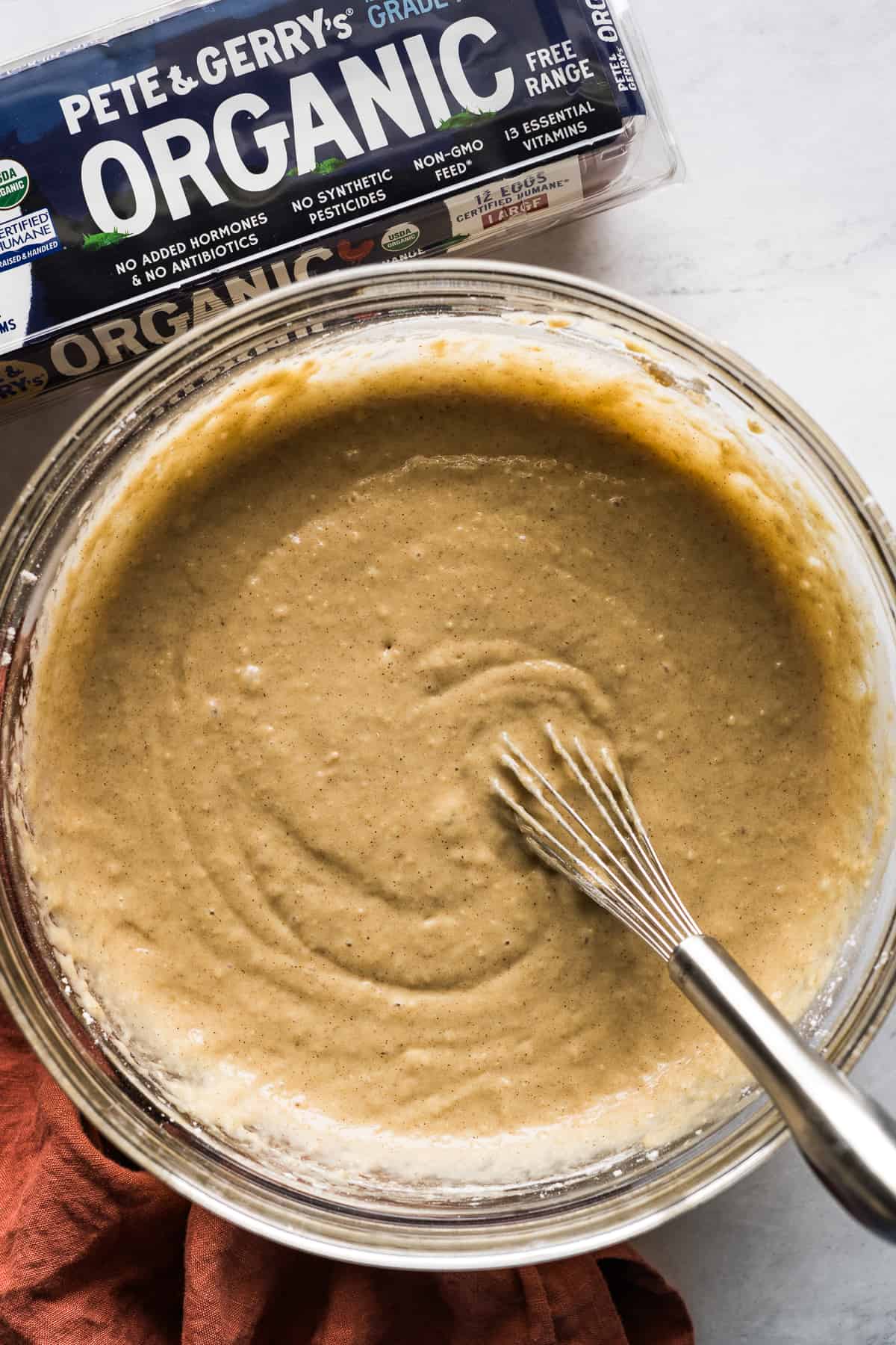 Cake batter on a table being whisked in a bowl.