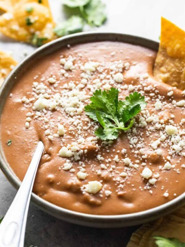 Frijoles puercos in a bowl garnished with cotija cheese and cilantro.