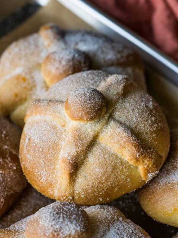 Pan de Muerto topped with granulated sugar on a baking sheet.