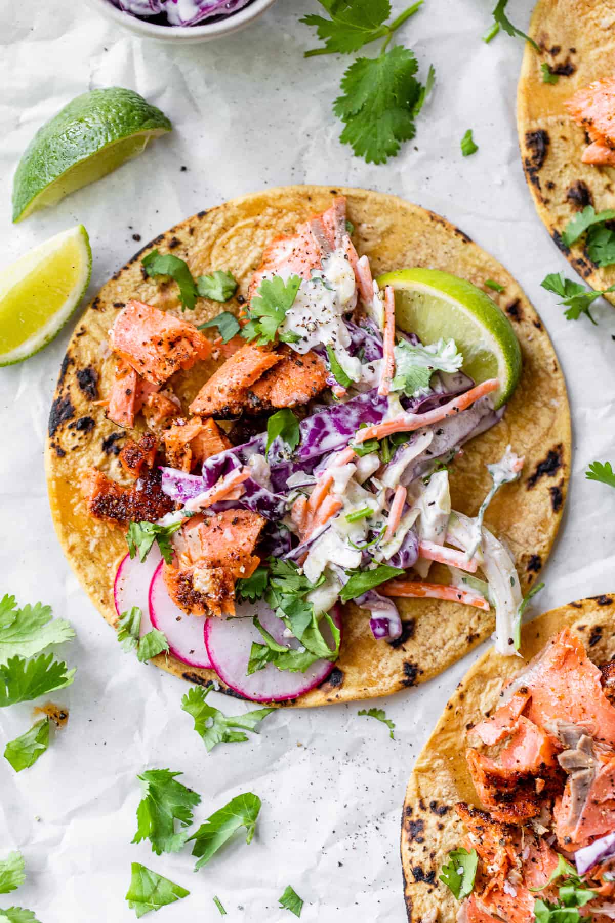 Salmon tacos topped with a cabbage slaw and garnished with chopped cilantro.