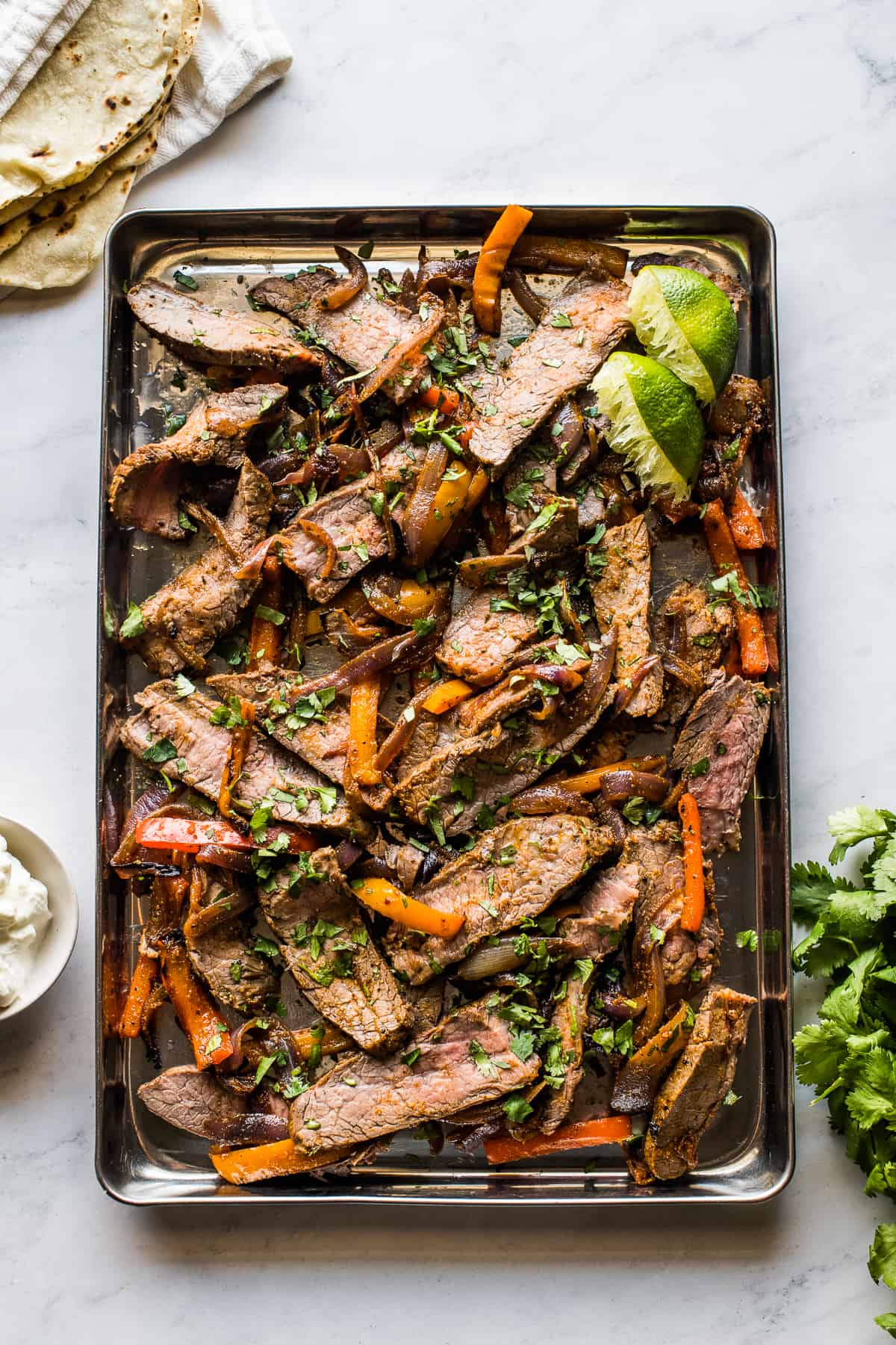 Sheet pan steak fajitas topped with chopped cilantro.