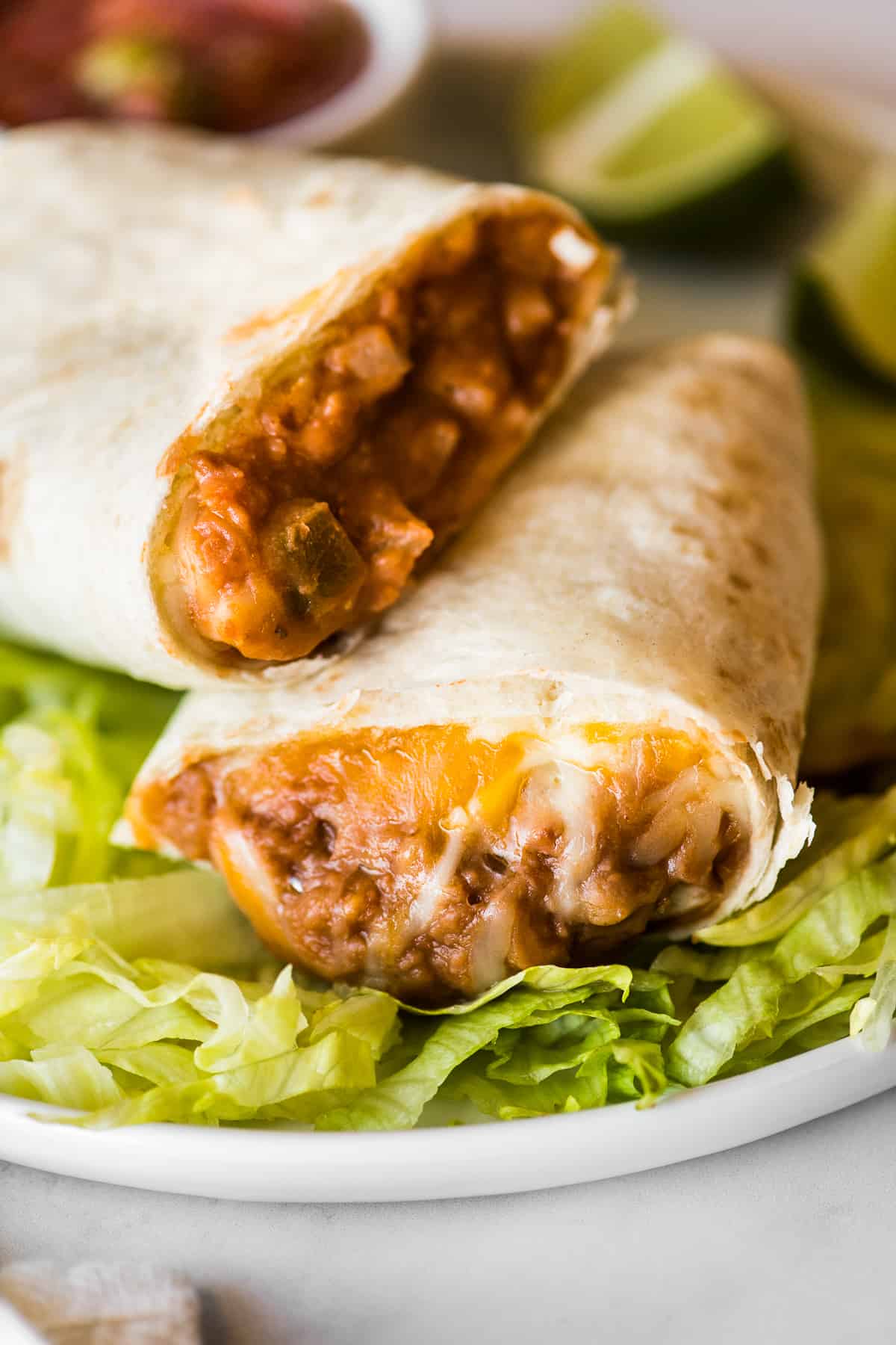 A bean and cheese burrito on a bed of shredded lettuce.
