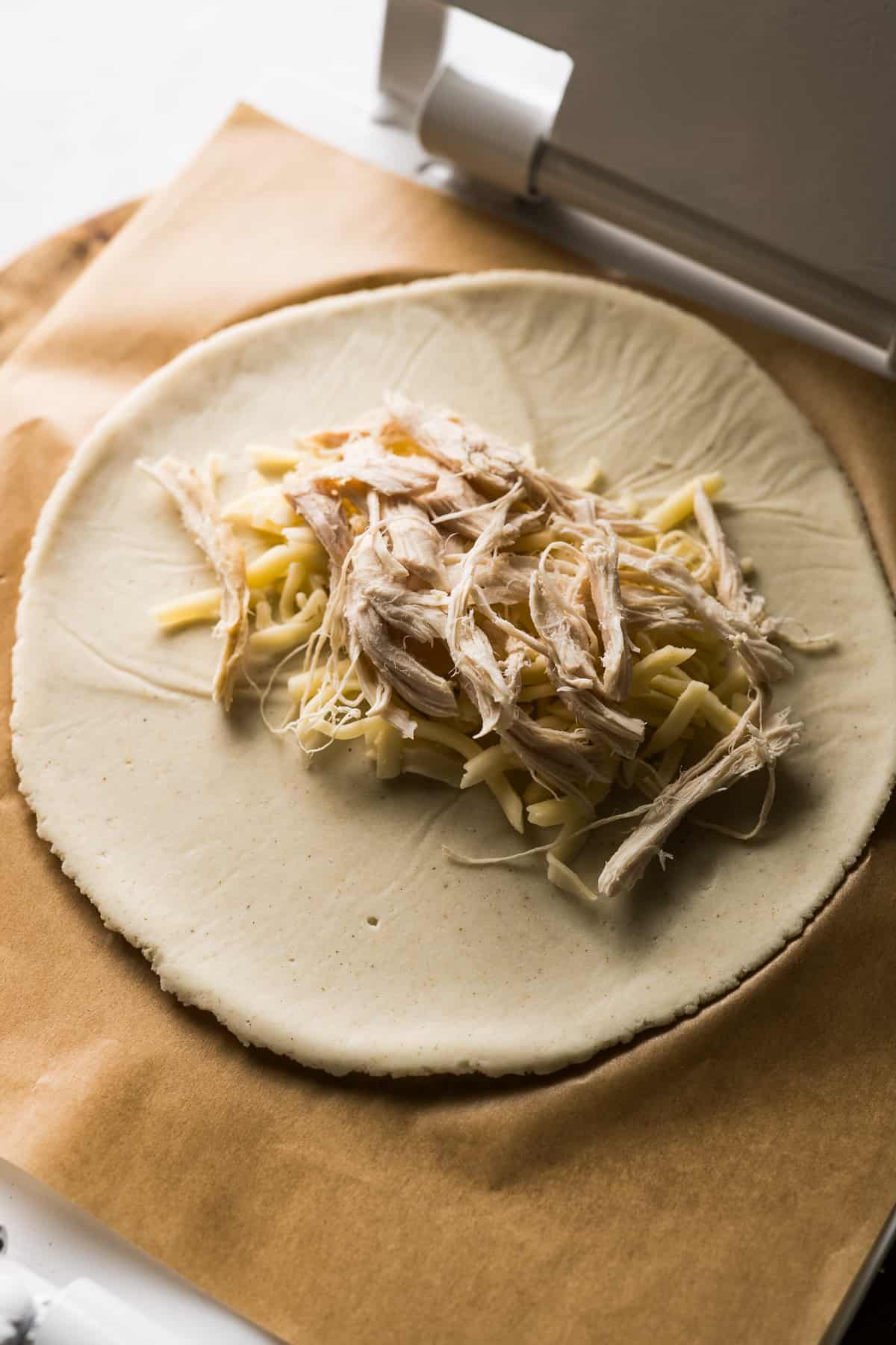 Shredded chicken and cheese in the middle of a circle of masa.