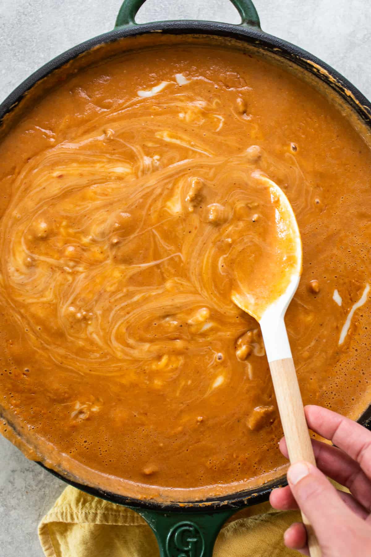 A wooden spoon stirring a skillet of frijoles puercos.