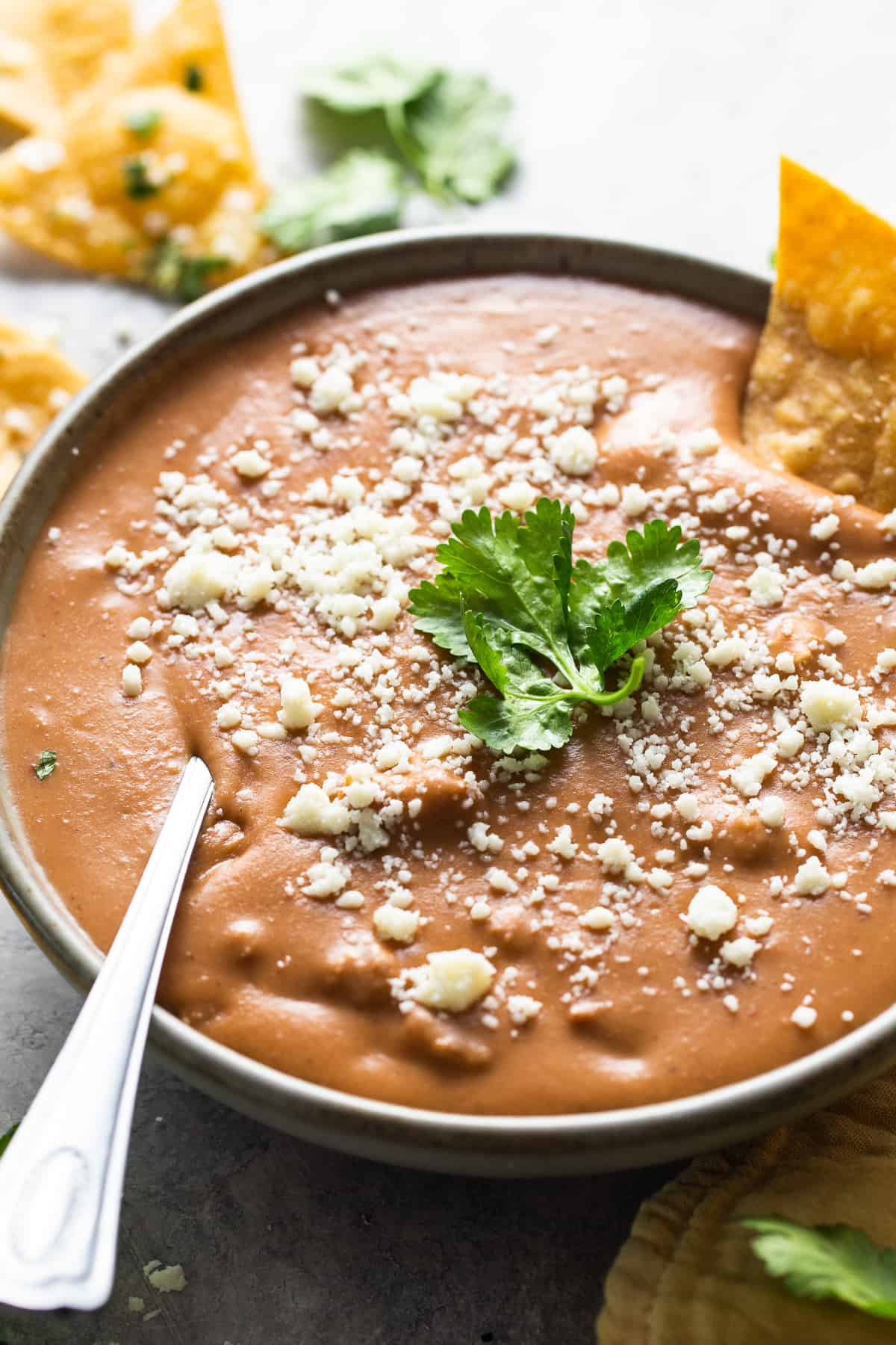 Frijoles puercos in a bowl garnished with cotija cheese and cilantro.