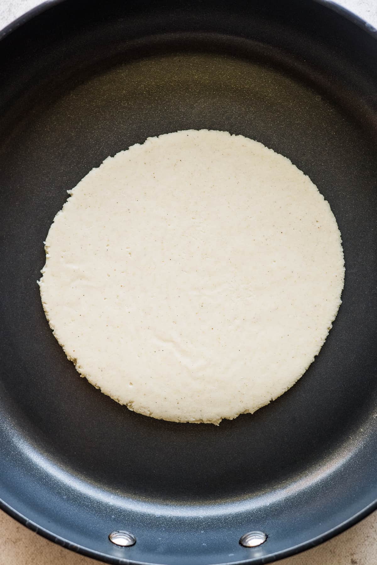 A gordita cooking in a skillet.