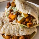 Gorditas stacked on top of one another filled with papas con chorizo and garnished with queso fresco and cilantro lime crema.