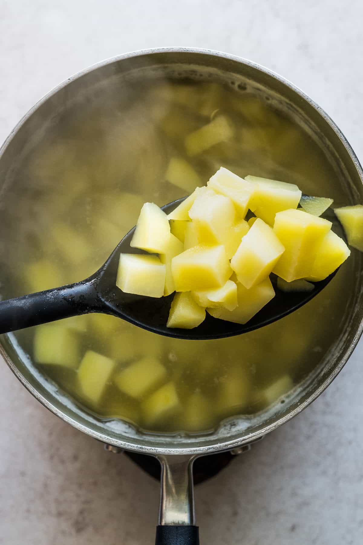 Cooked and tender potatoes on a spoon.