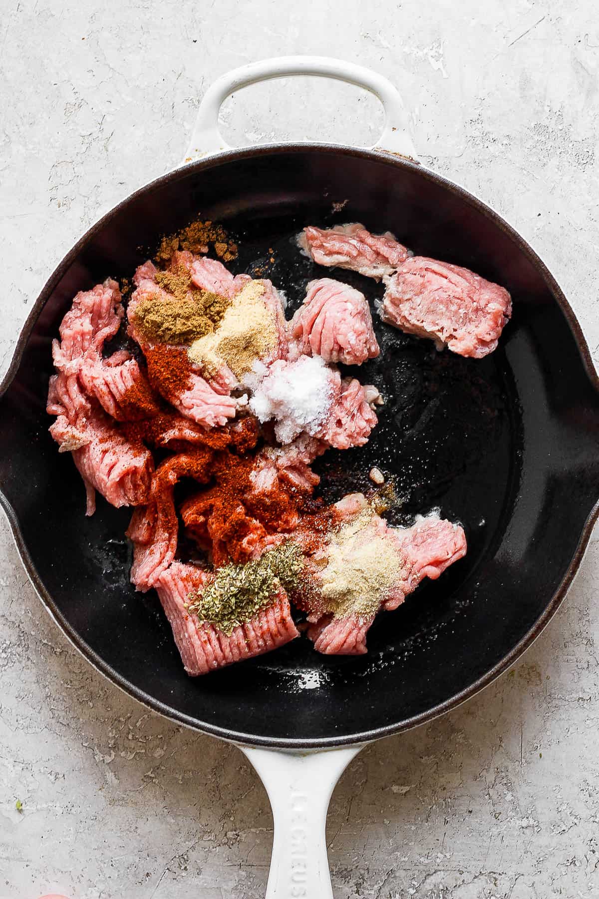 Ground turkey in a skillet with taco seasoning on top.