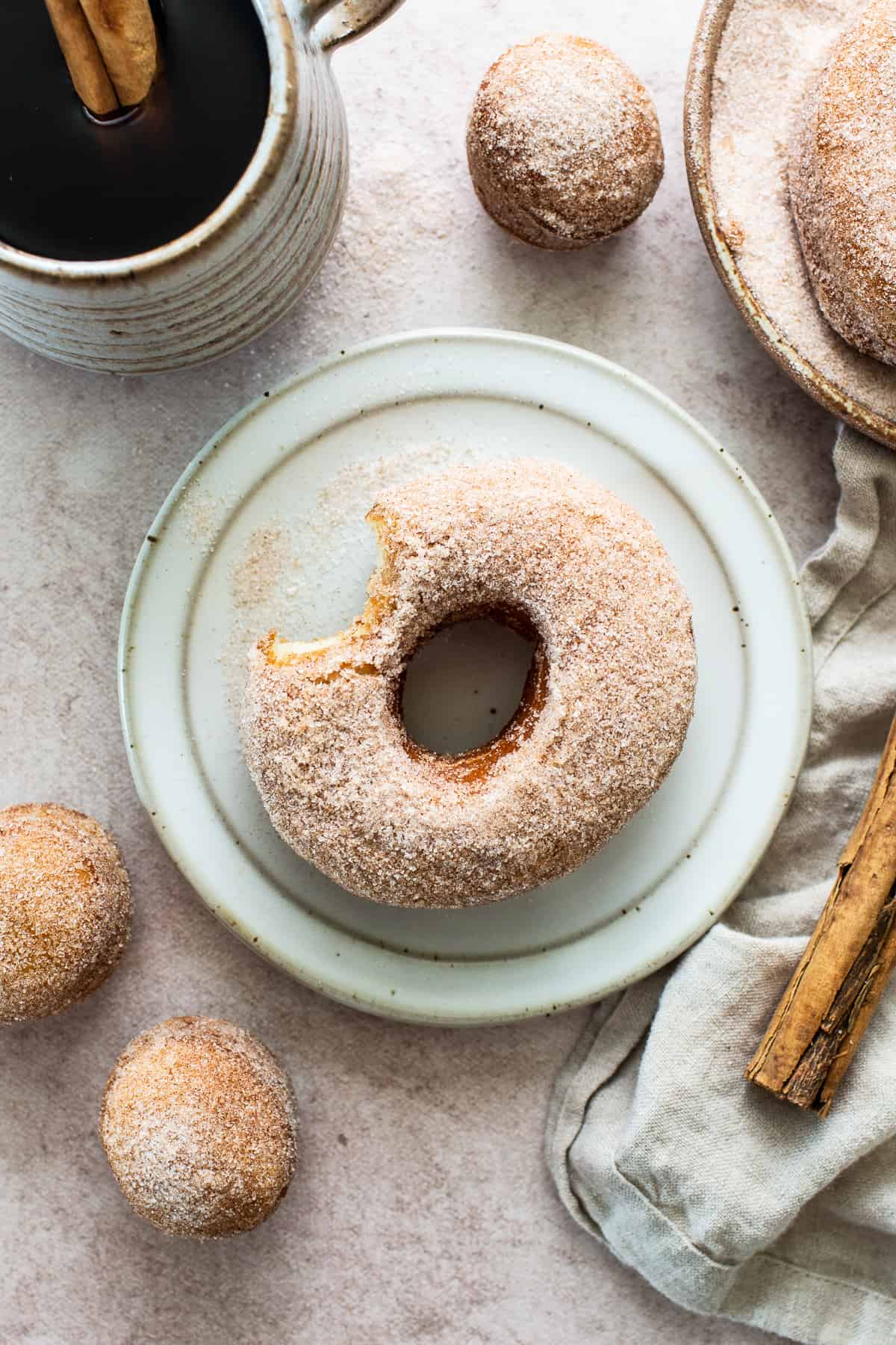 A Mexican donut on a plate with a bite taken out of it.