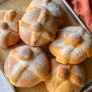 Pan de muerto loaves on a baking sheet.