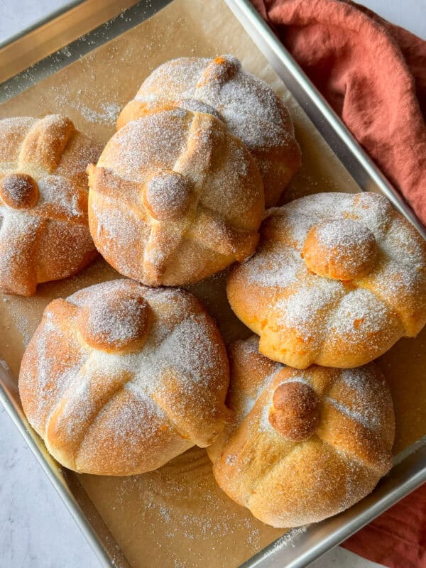 Pan de muerto loaves on a baking sheet.