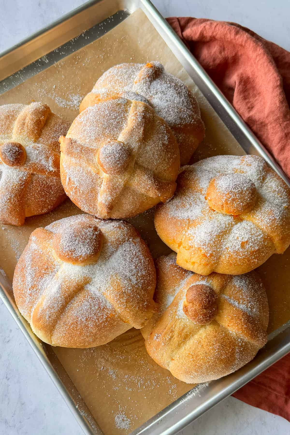 Pan de muerto loaves on a baking sheet.