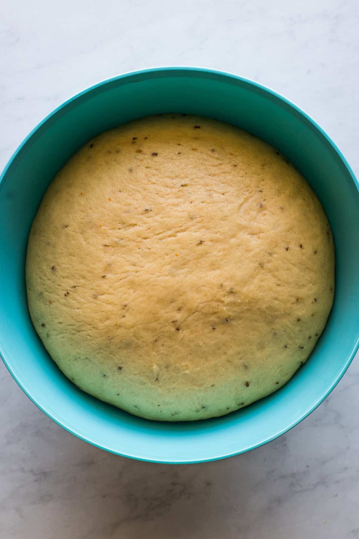 Pan de muerto dough rising in a large bowl.
