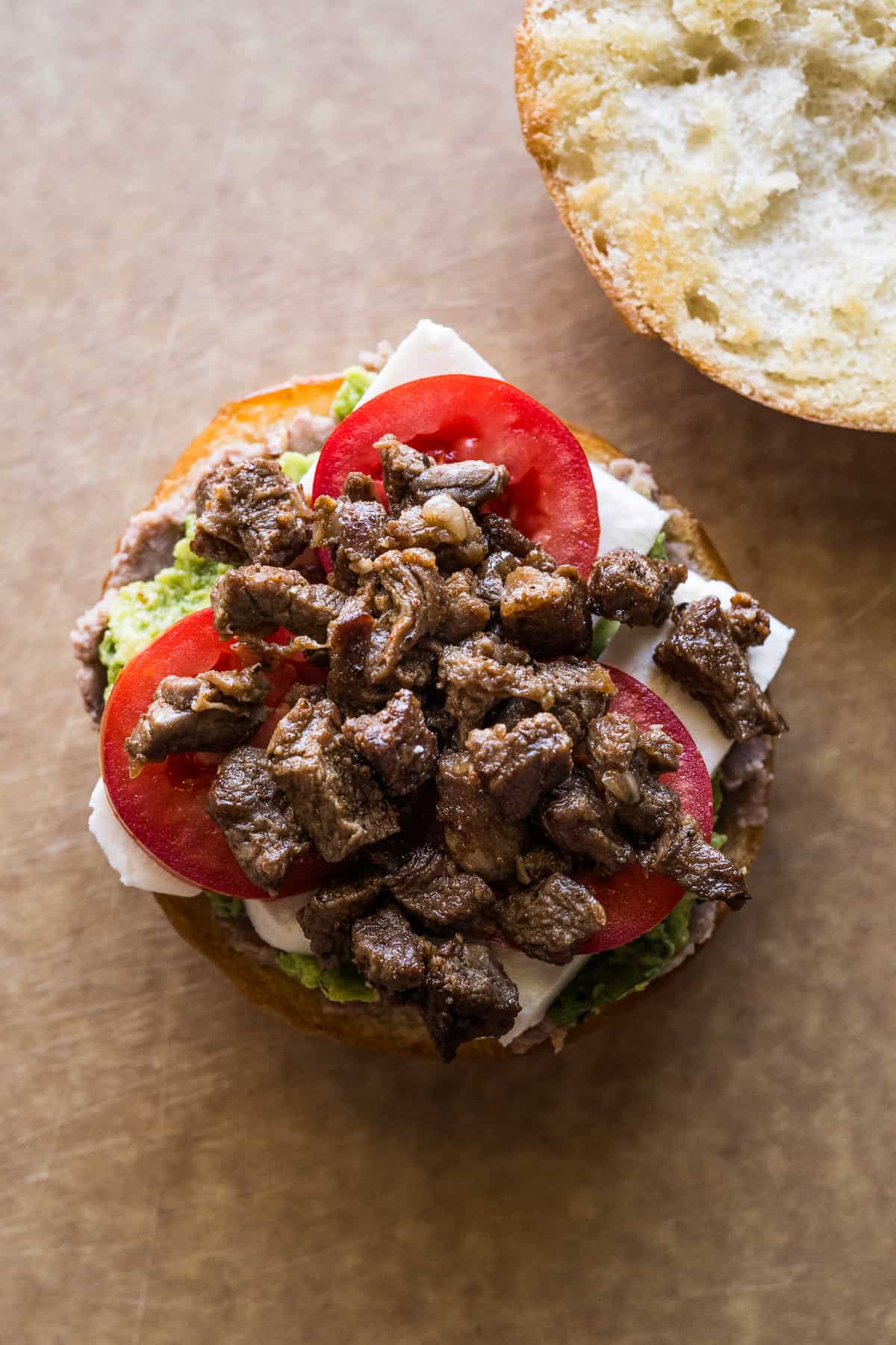 Chuck steak, tomatoes, queso fresco, refried beans and guacamole smeared on a telera roll.