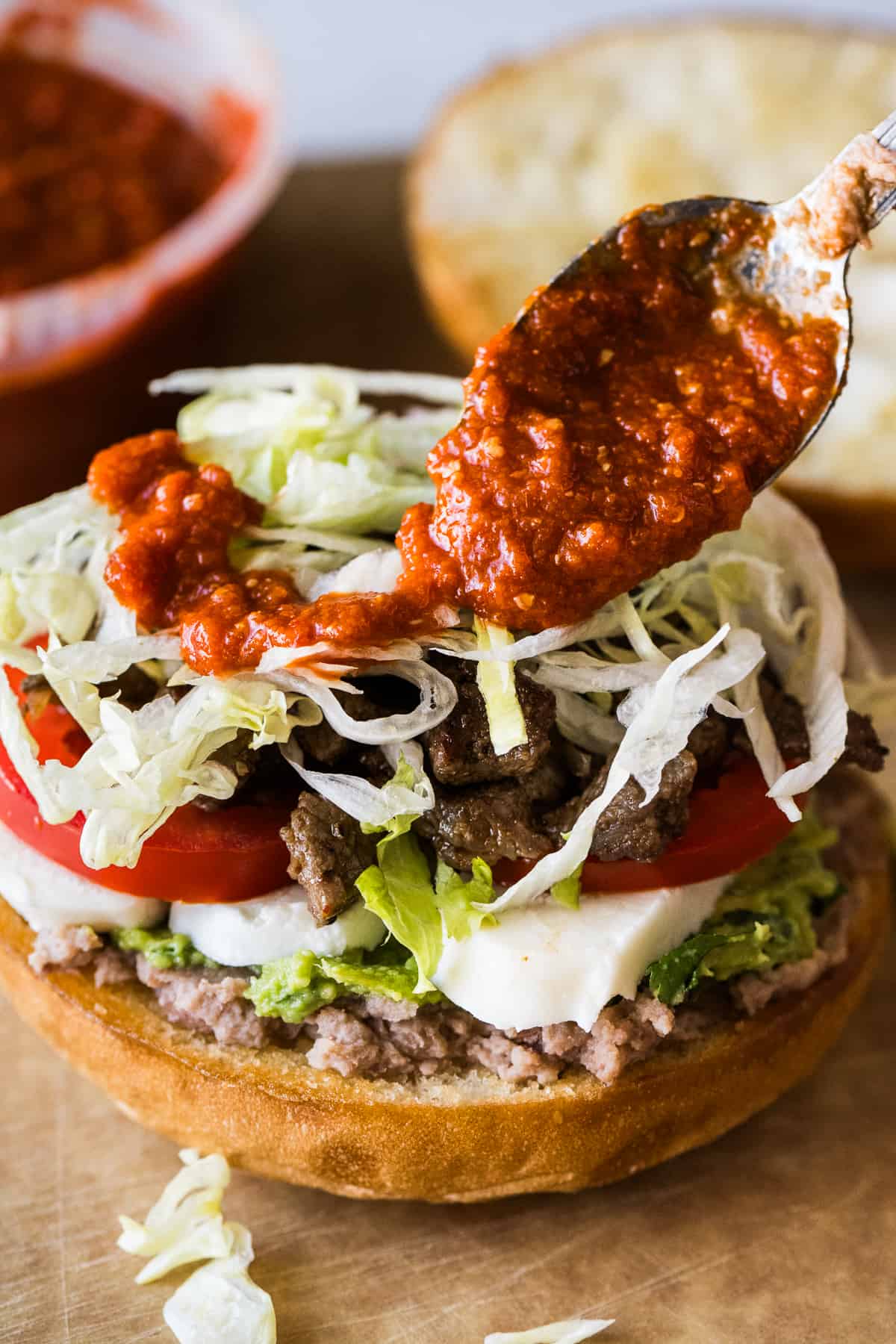 Red salsa being drizzled on a torta.