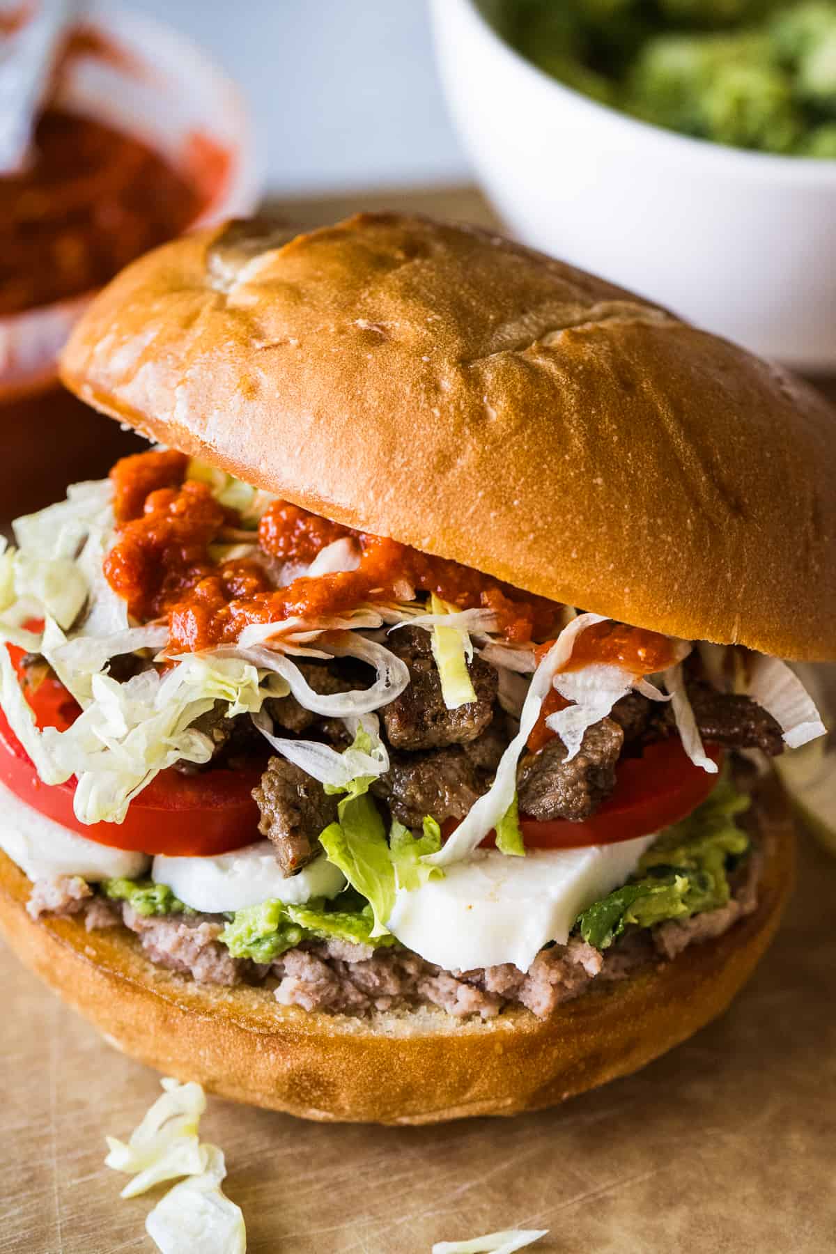 A torta Mexican sandwich filled with refried beans, guacamole, queso fresco, tomato, steak, lettuce, and salsa.