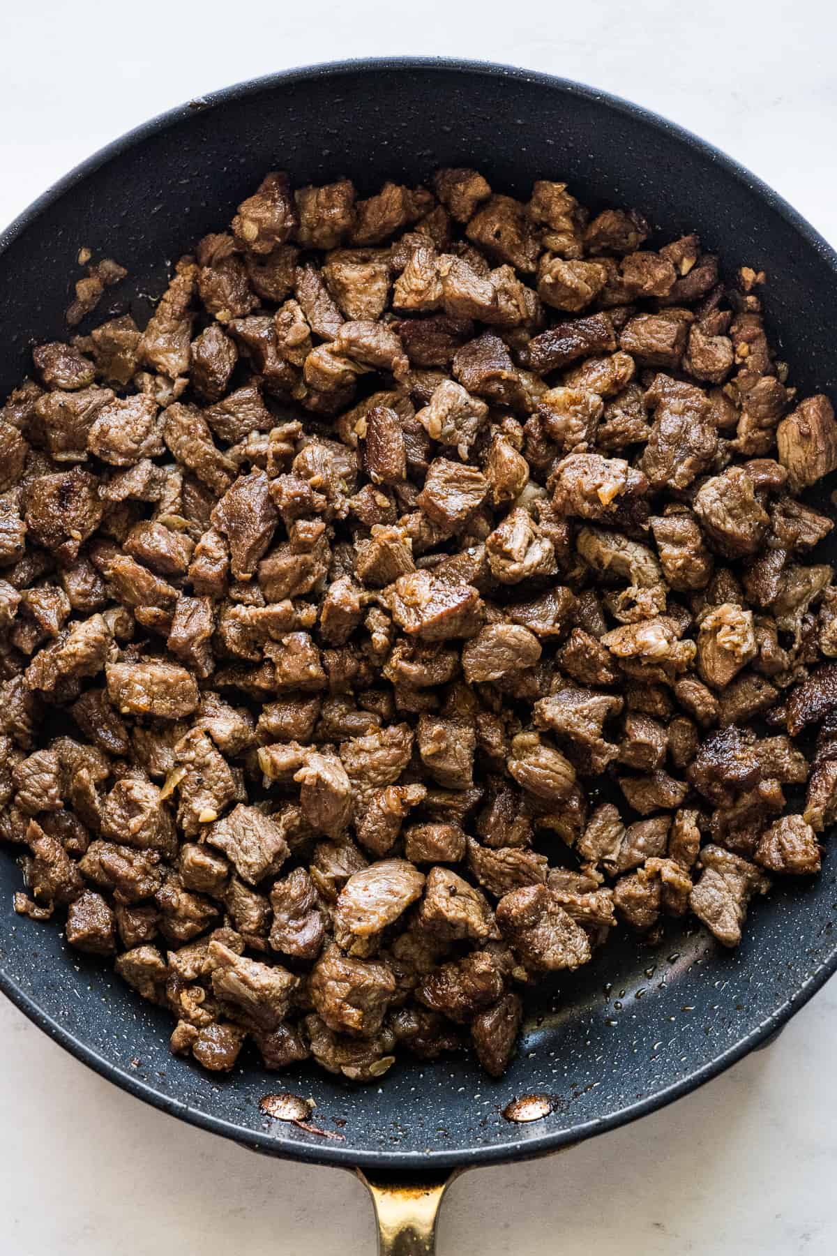 Cooked chuck steak in a skillet ready to be used as a filling in Mexican tortas.