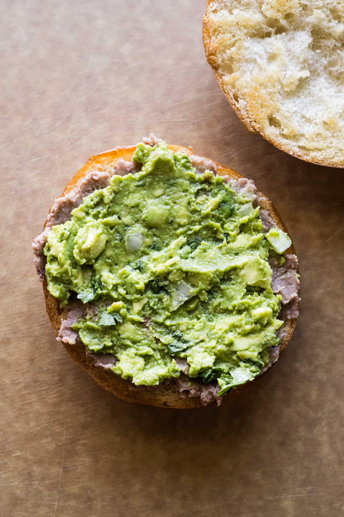 Refried beans and guacamole smeared on a telera roll.