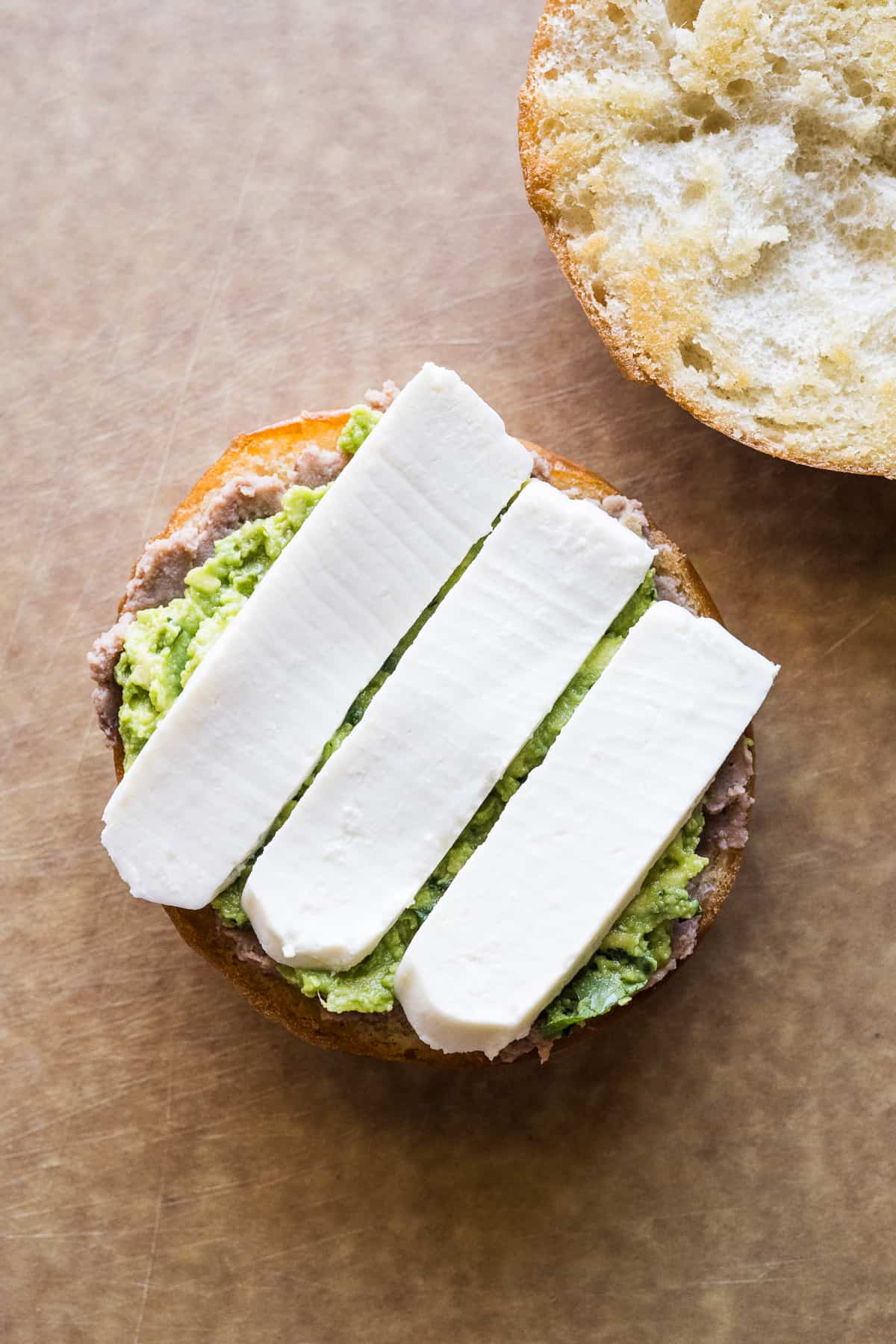 Queso fresco, refried beans and guacamole smeared on a telera roll.
