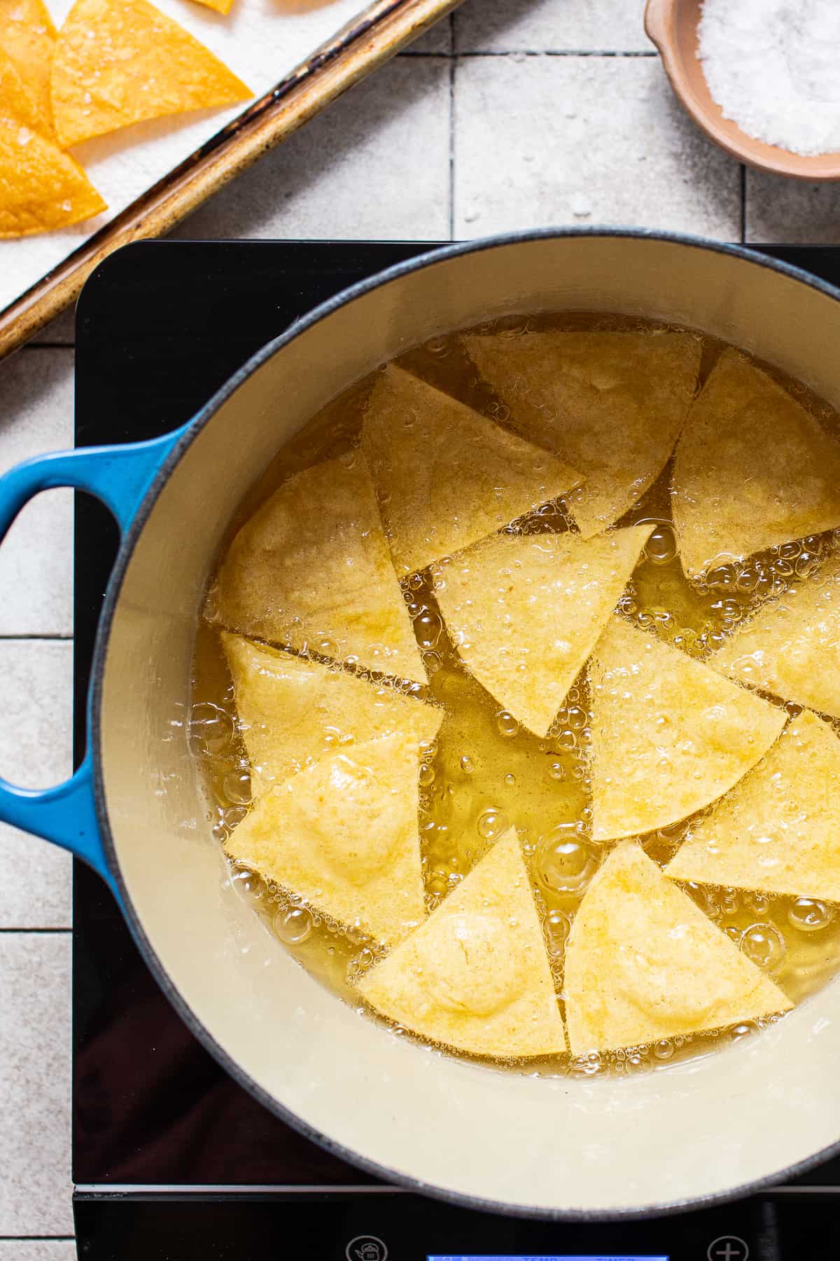 Corn tortillas frying in a pot.