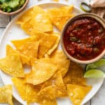 Homemade tortilla chips on a plate seasoned with flaky sea salt.
