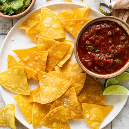 Homemade tortilla chips on a plate seasoned with flaky sea salt.