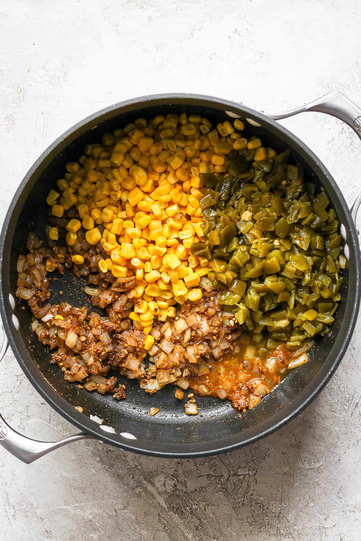 Corn and diced green chiles cooking in a pot for white chicken chili.