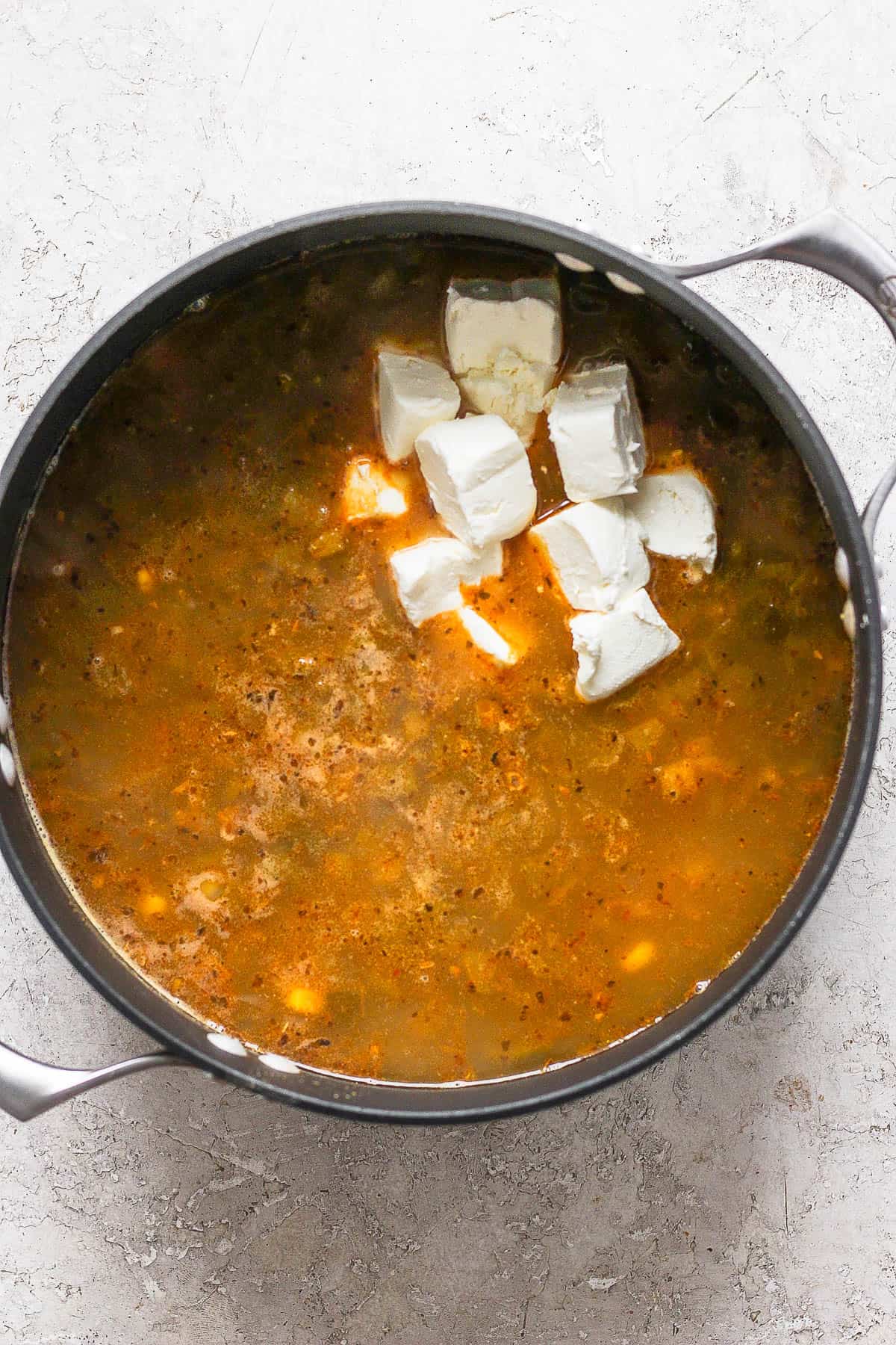 Cream cheese being stirred into a pot of white chicken chili.