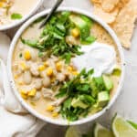 White chicken chili in a bowl garnished with cilantro, avocado, and sour cream.