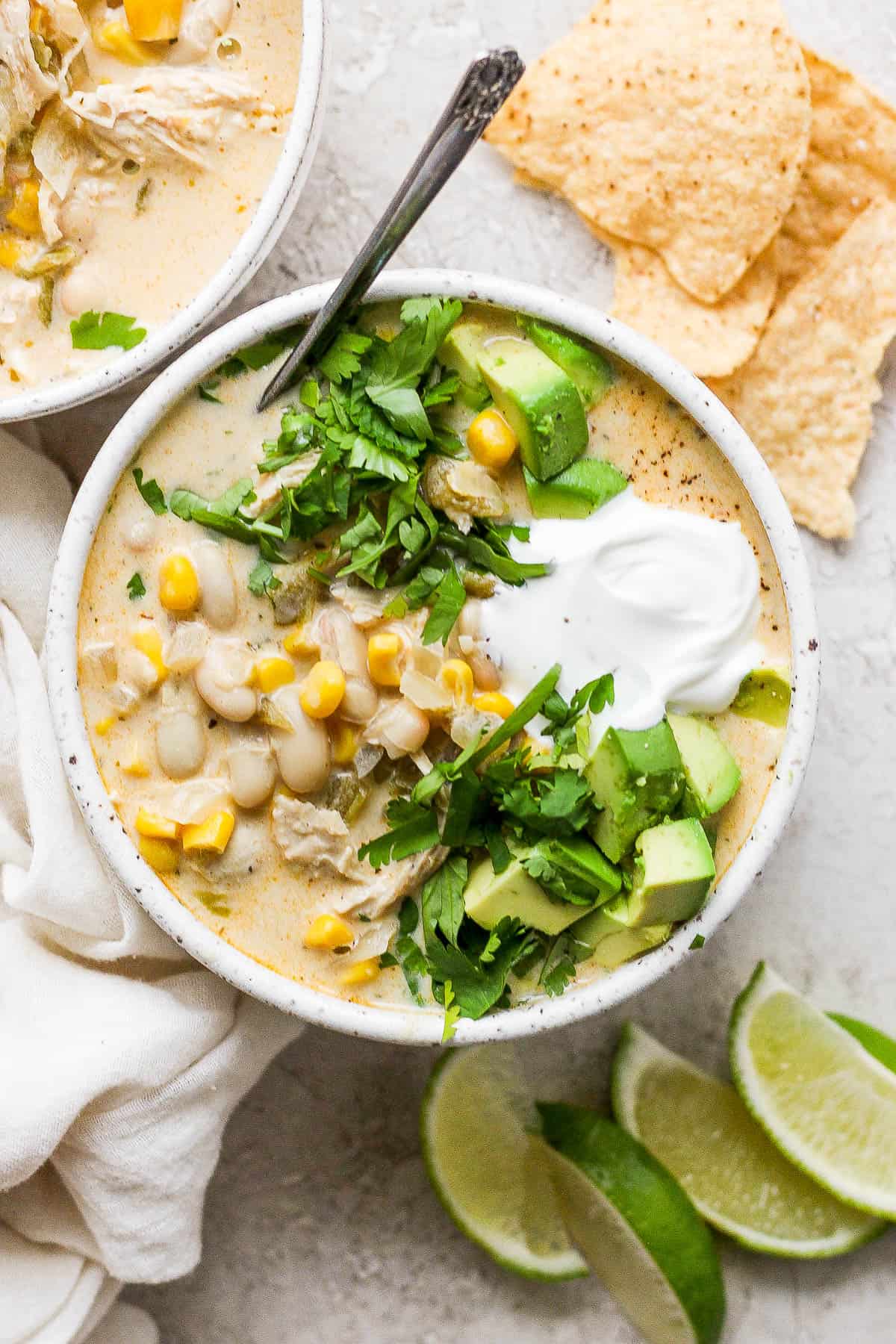 White chicken chili in a bowl garnished with cilantro, avocado, and sour cream.