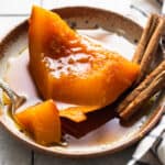 A slice of tender calabaza en tacha on a plate served with a piloncillo syrup.