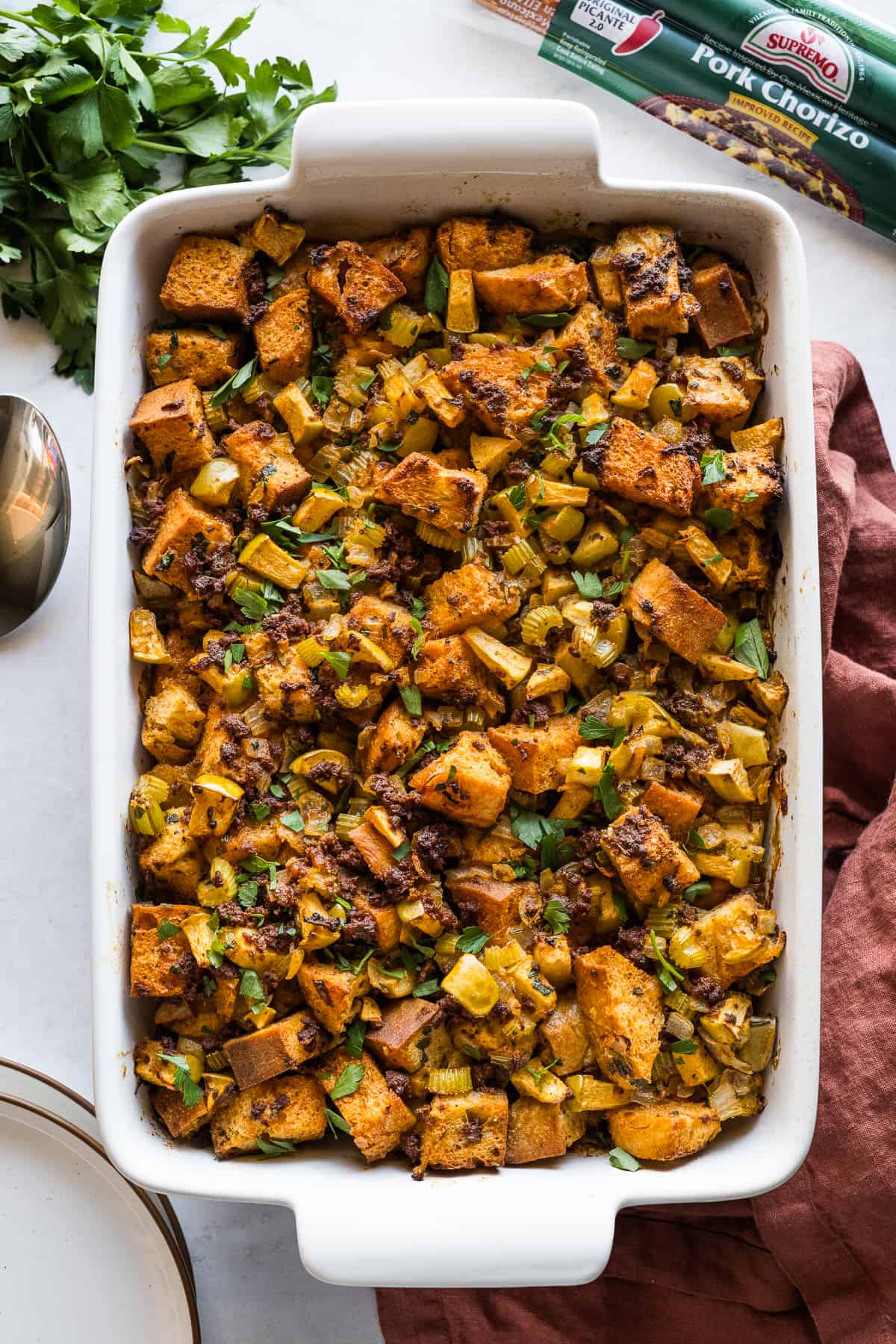 A baking dish containing Chorizo stuffing garnished with fresh parsley.