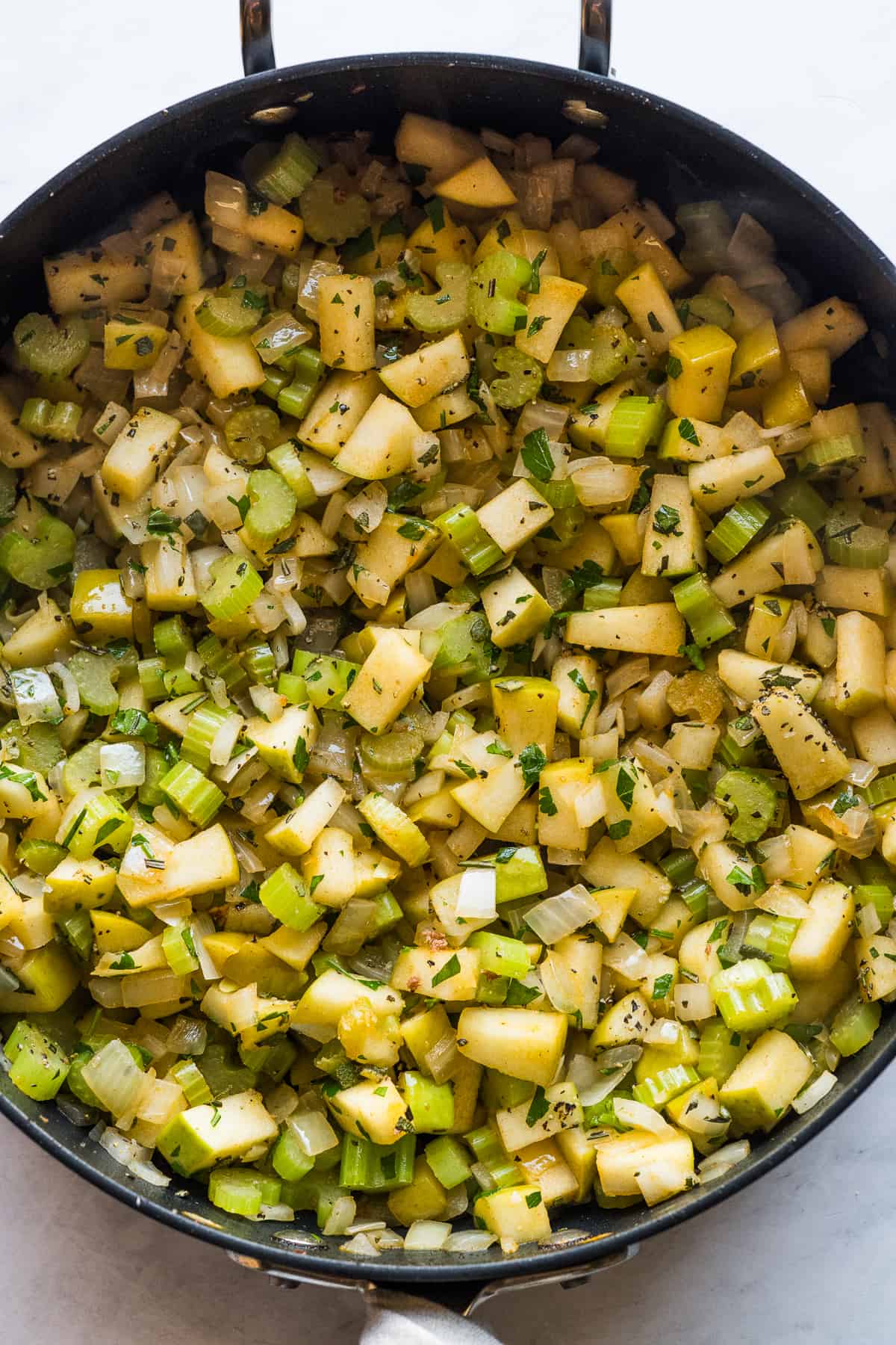 A skillet of cooked celery, onions and apples