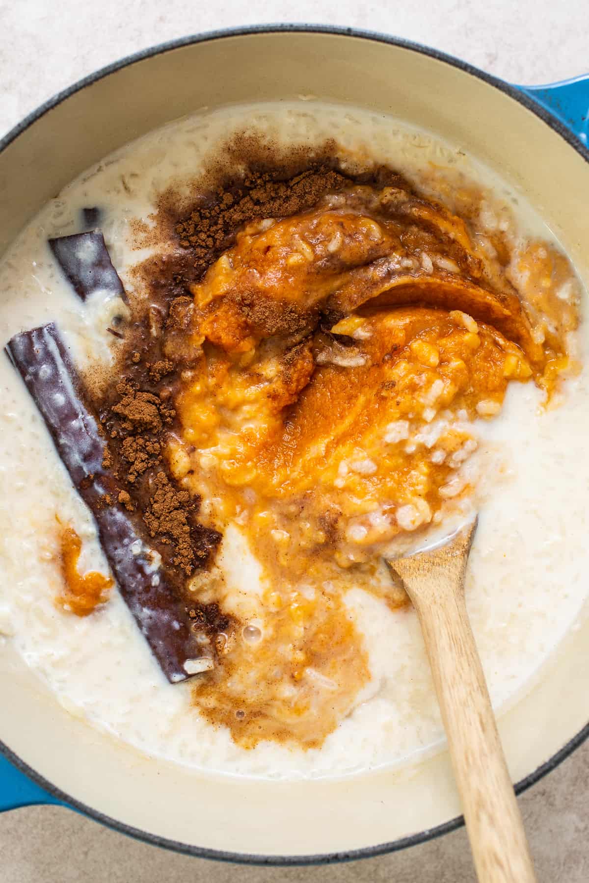 Pumpin puree and pumpkin pie spice being mixed into cooked rice to make pumpkin arroz con leche.