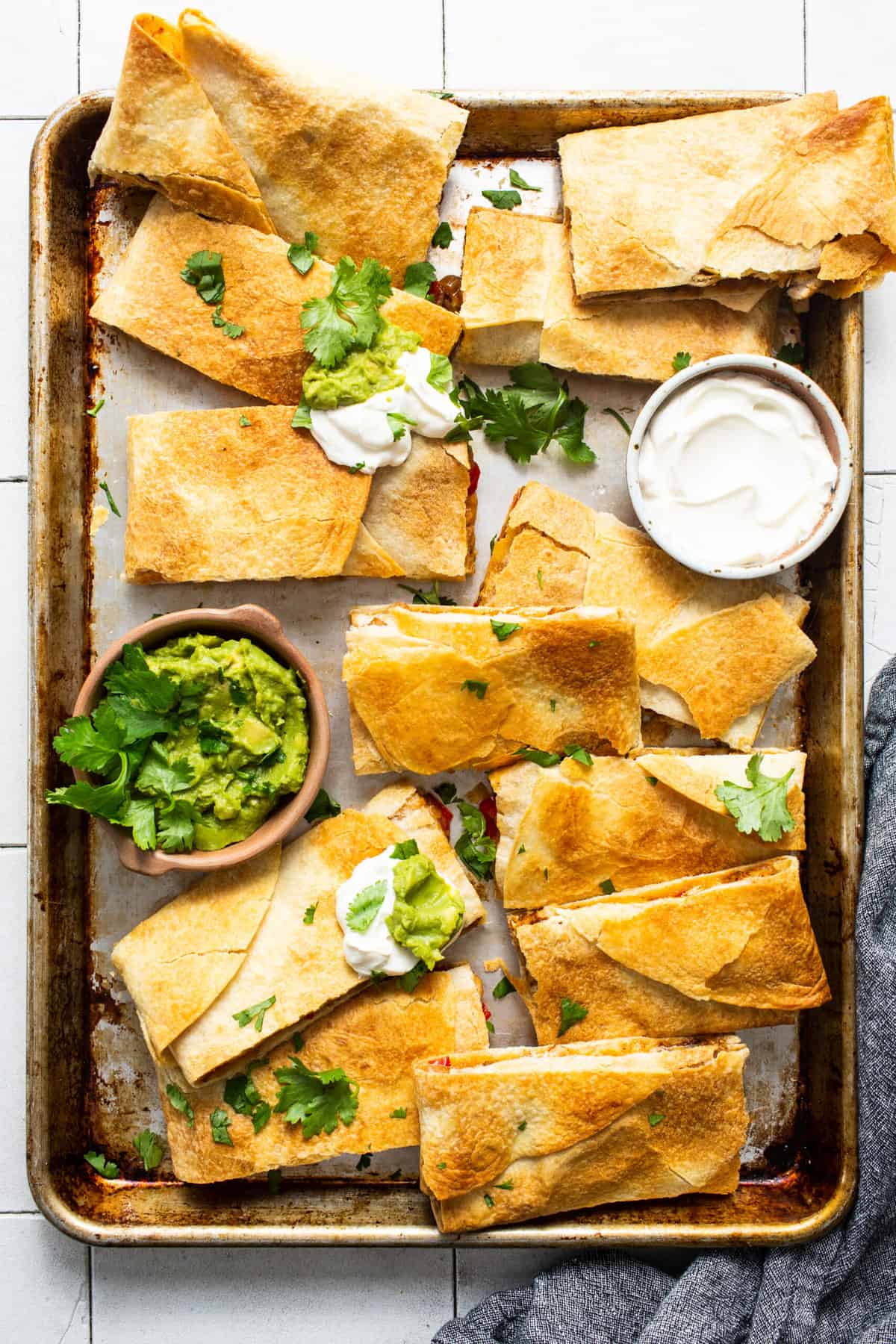 Sheet pan quesadillas on a sheet pan served with sour cream and guacamole.