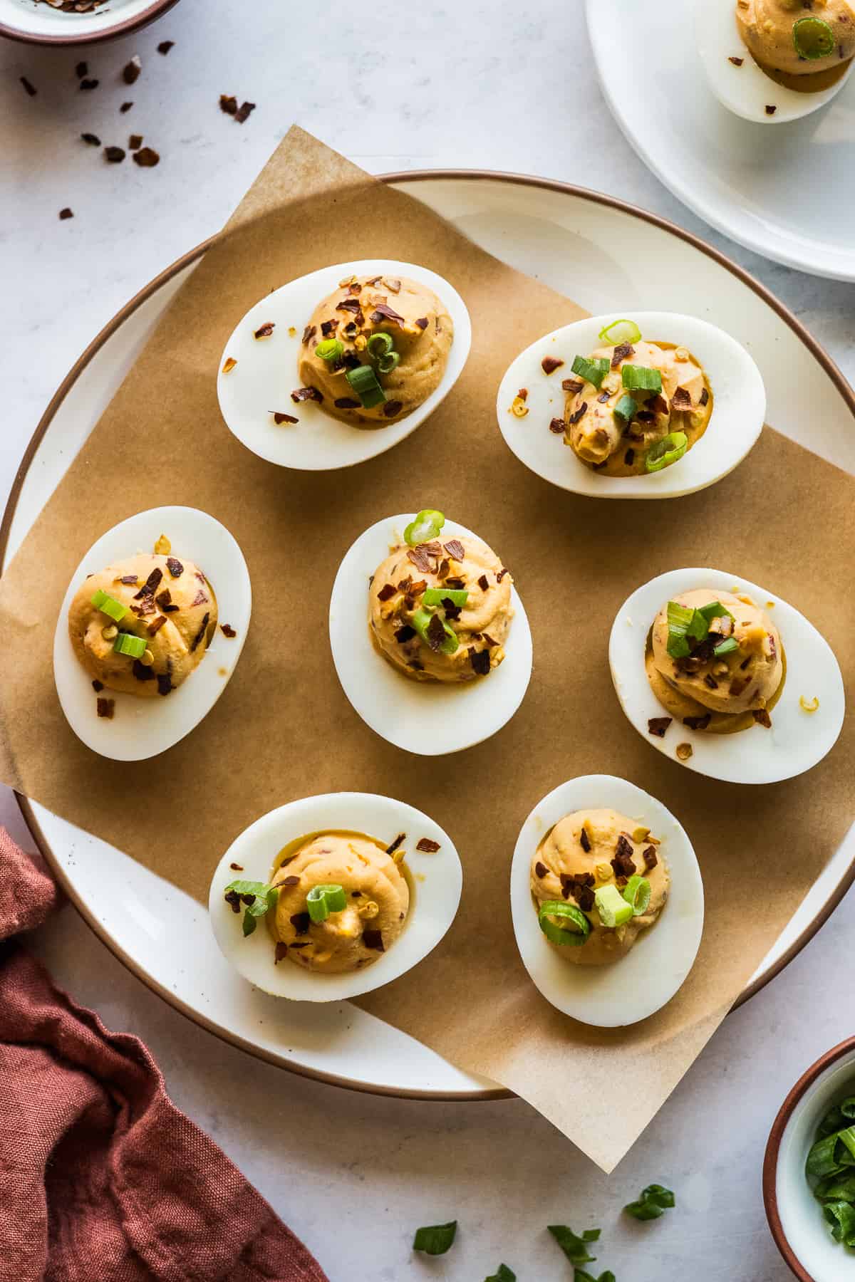 Spicy chipotle deviled eggs garnished with crushed red pepper flakes and green onions.