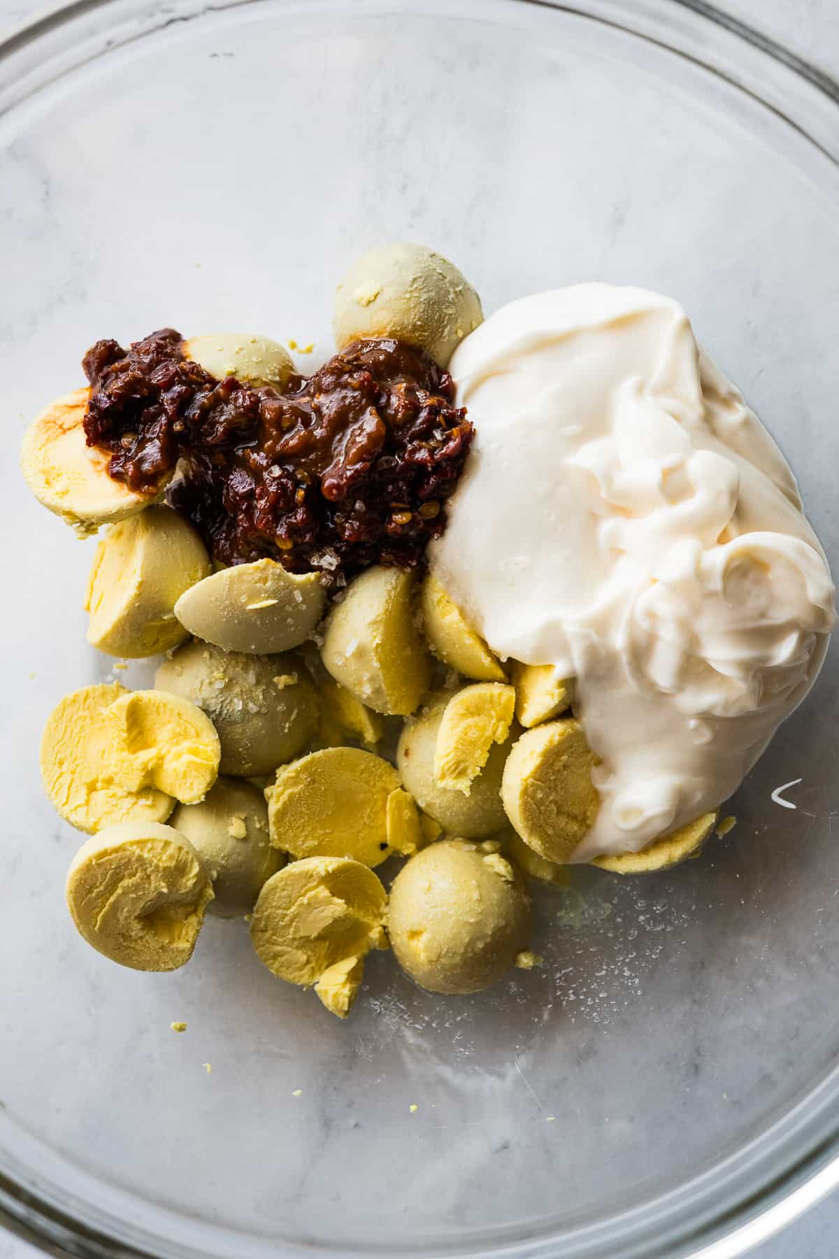 Hard boiled egg yolks, mayonnaise, and chipotle peppers in adobo in a bowl.