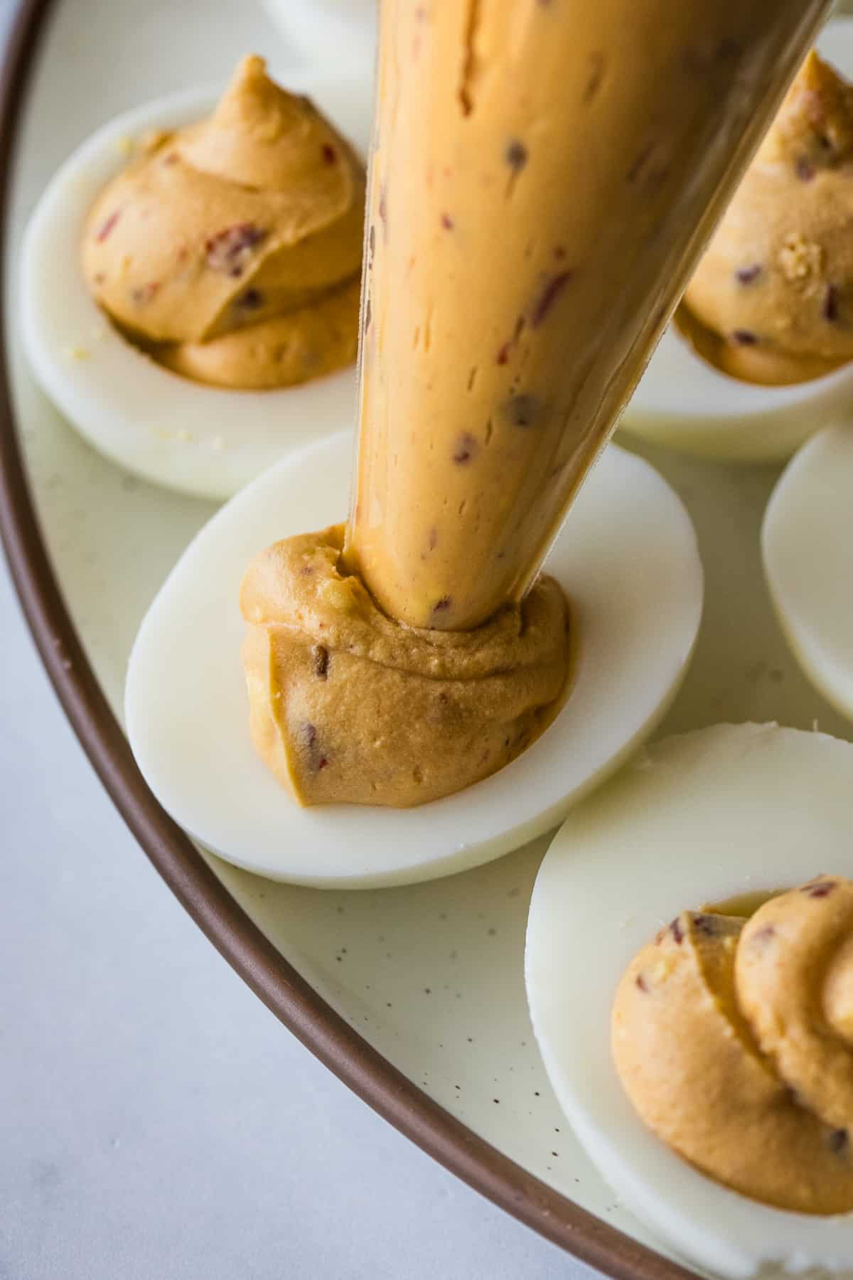 Filling for spicy deviled eggs being put into hard boiled egg whites.