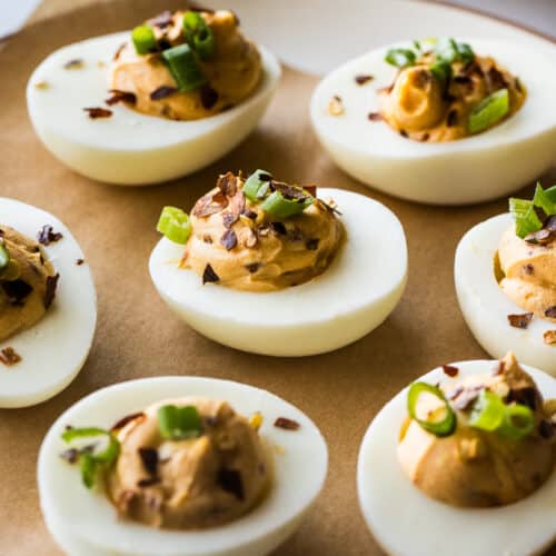 Spicy deviled eggs on a plate garnished and ready to be eaten.
