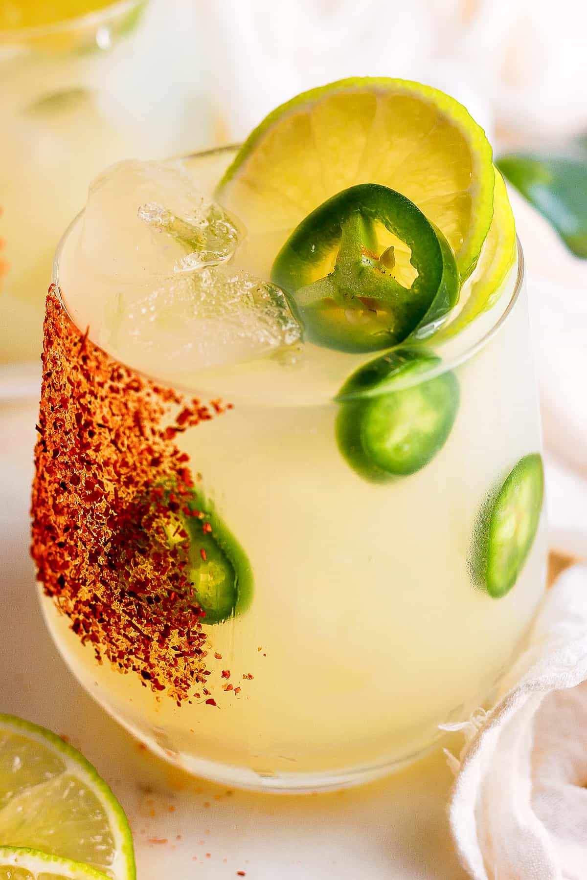 Spicy margaritas garnished with tajin, jalapeno, and lime.